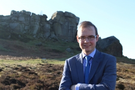 Photo of Ilkley candidate Kyle Green, standing in fromt of the famous Cow and Calf Rocks, Ilkley.